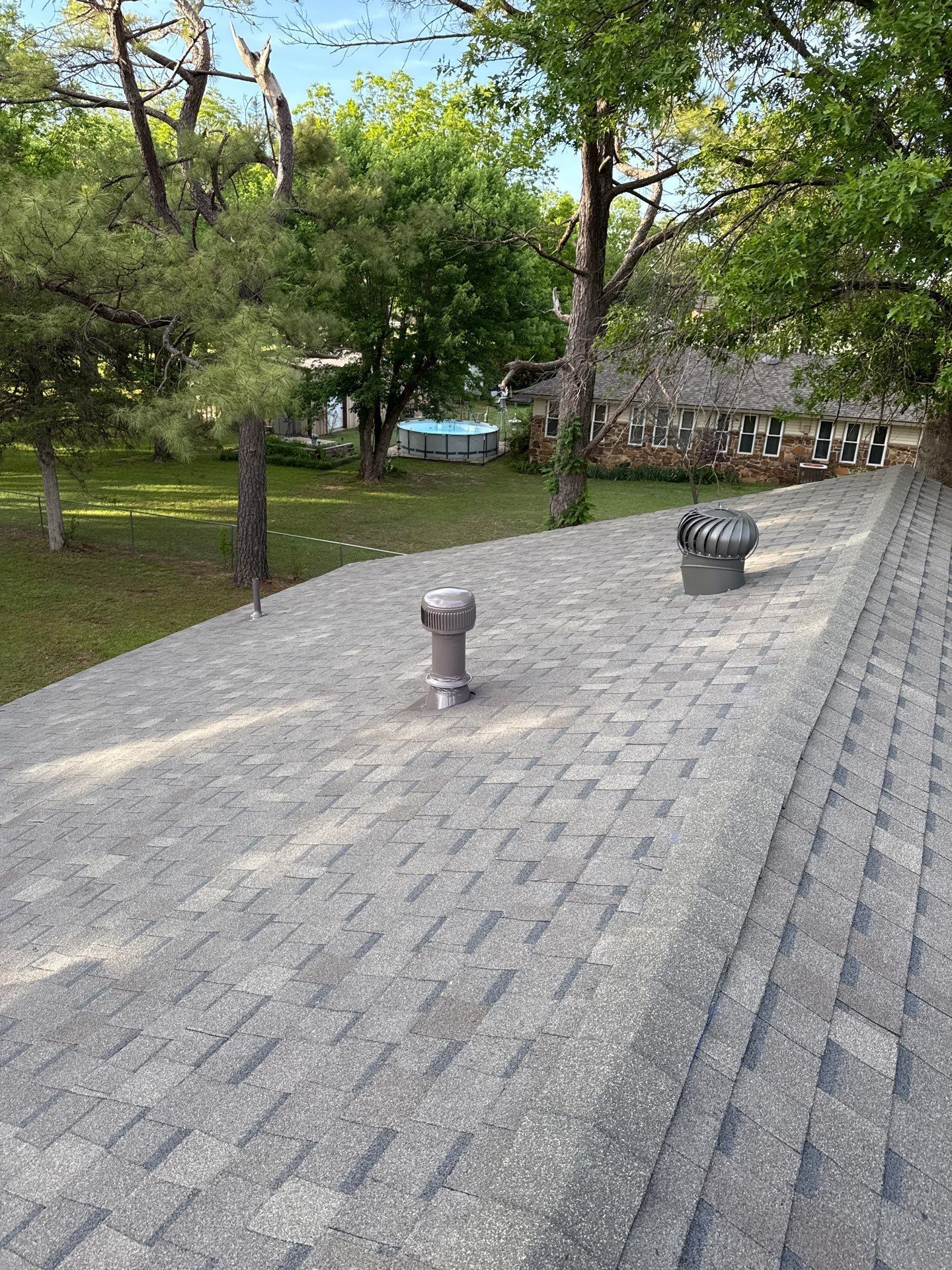 A roof with a chimney on it and trees in the background.