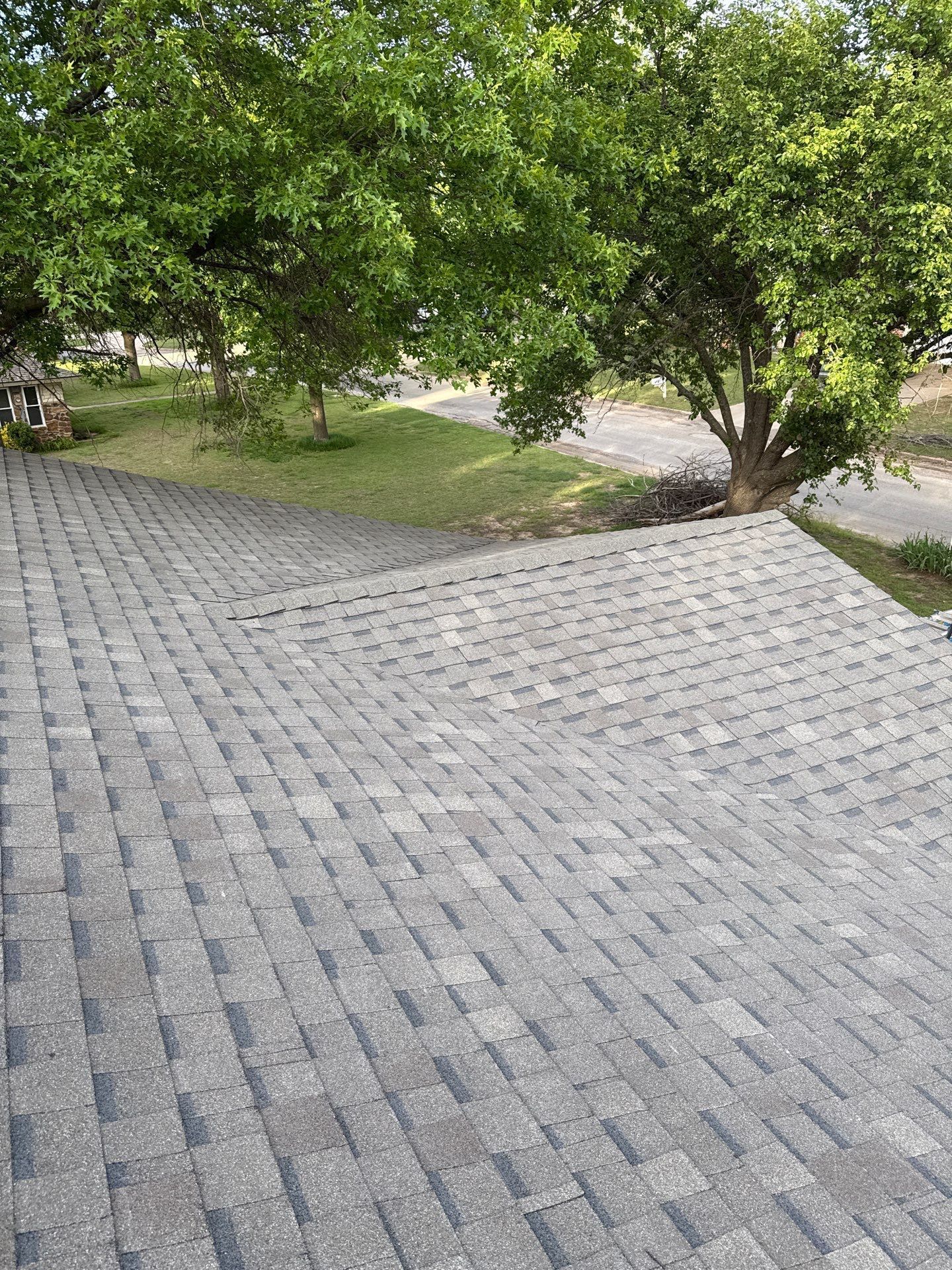A roof with a lot of shingles and trees in the background.