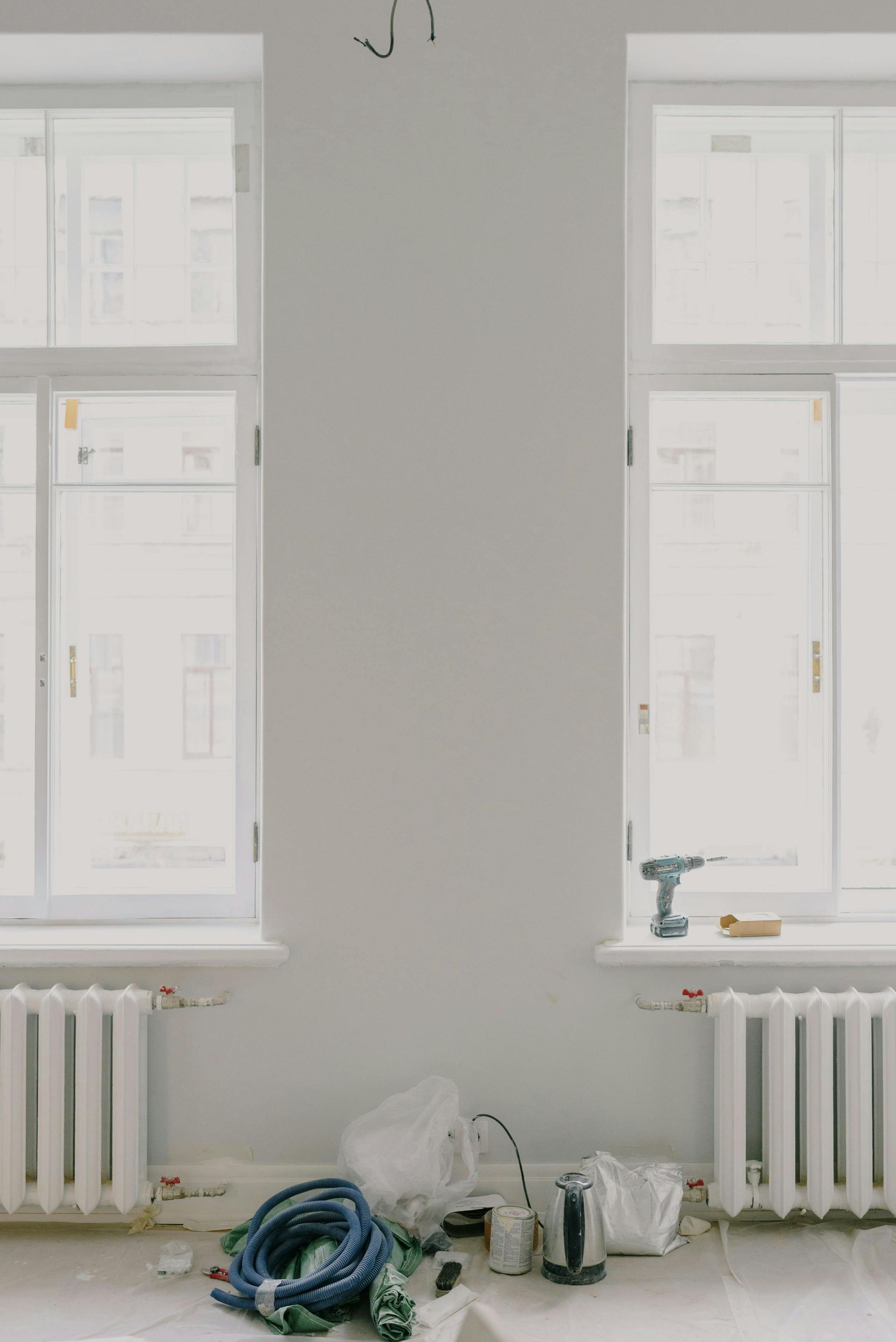 A room with two windows and radiators under construction.