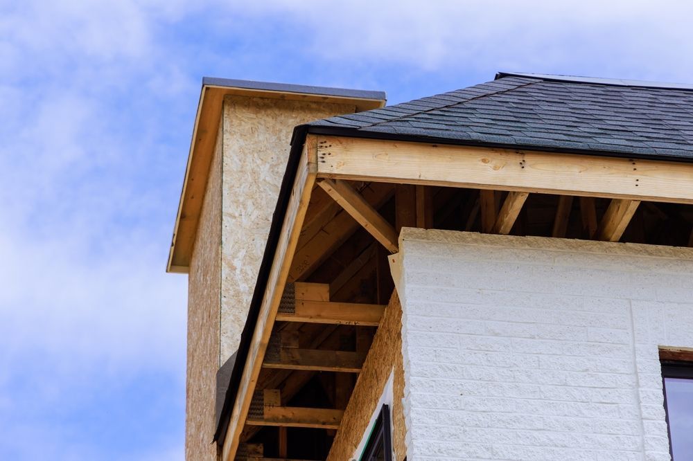 A house is being built with a wooden roof and a blue sky in the background.