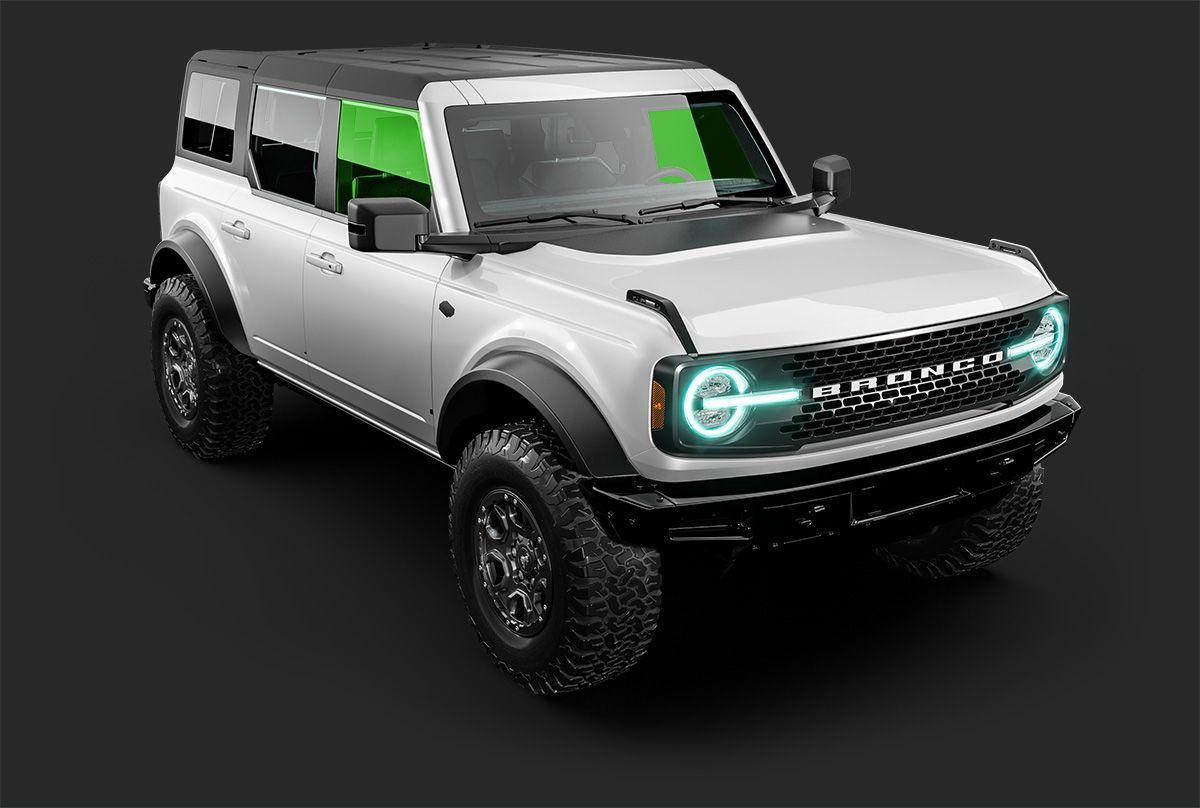White Ford Bronco SUV with black accents, green tinted windows, and glowing headlights.