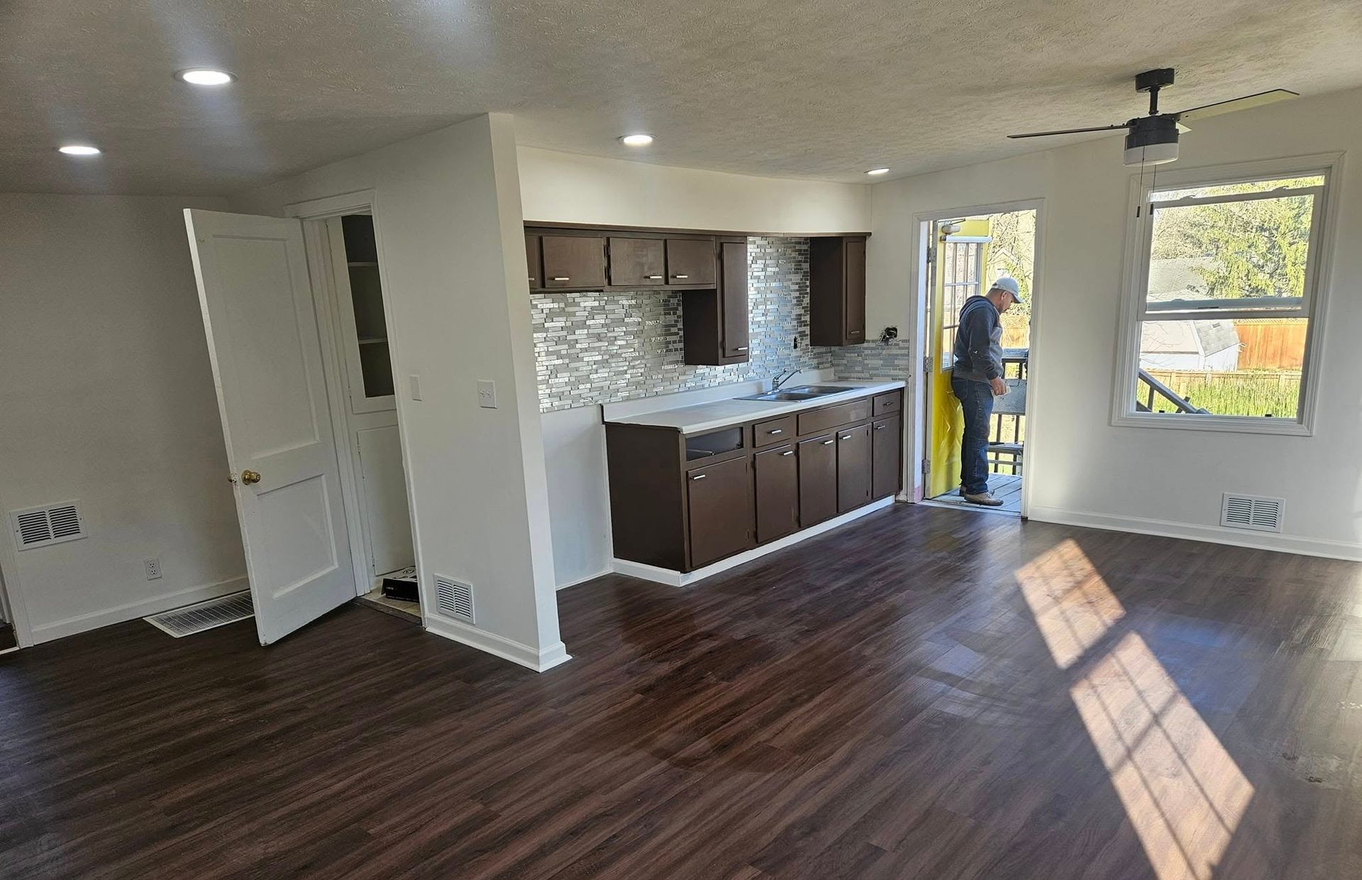A man is standing in a living room next to a kitchen.
