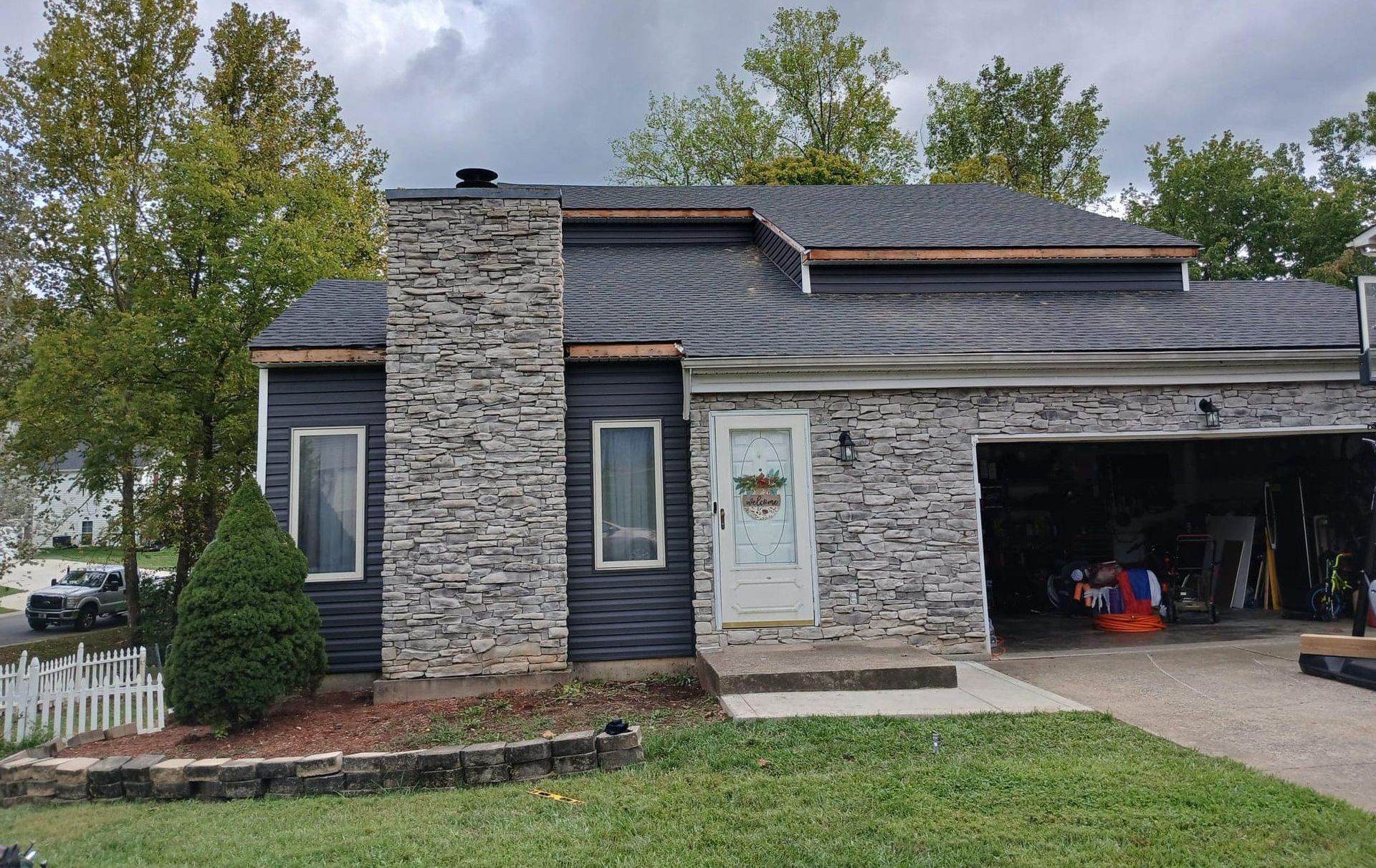 A house with a stone chimney on the side of it and a garage.