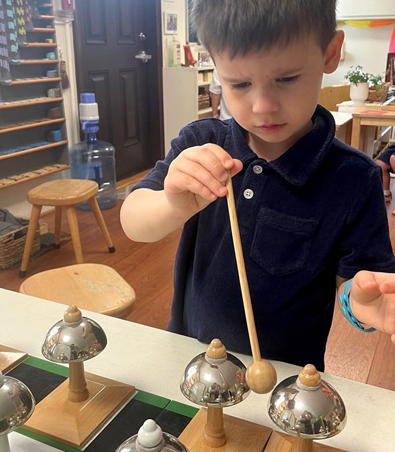 a Montessori child is playing with bells in a classroom