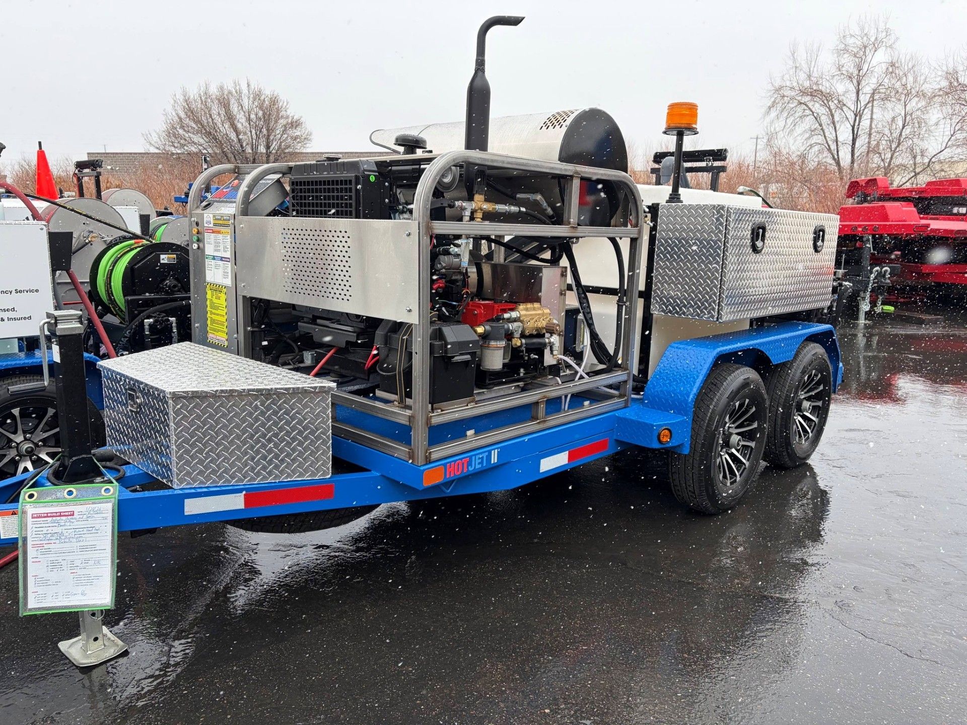 Blue trailer with industrial equipment and metal storage boxes parked on a wet lot