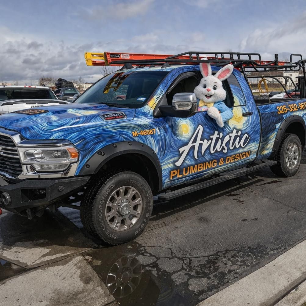 Blue Artistic Plumbing & Drains pickup with a large bunny decal, parked in a lot under cloudy skies