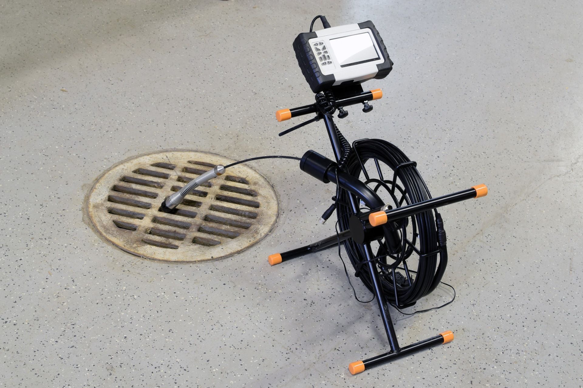 Black cable inspection camera on pavement beside a manhole cover