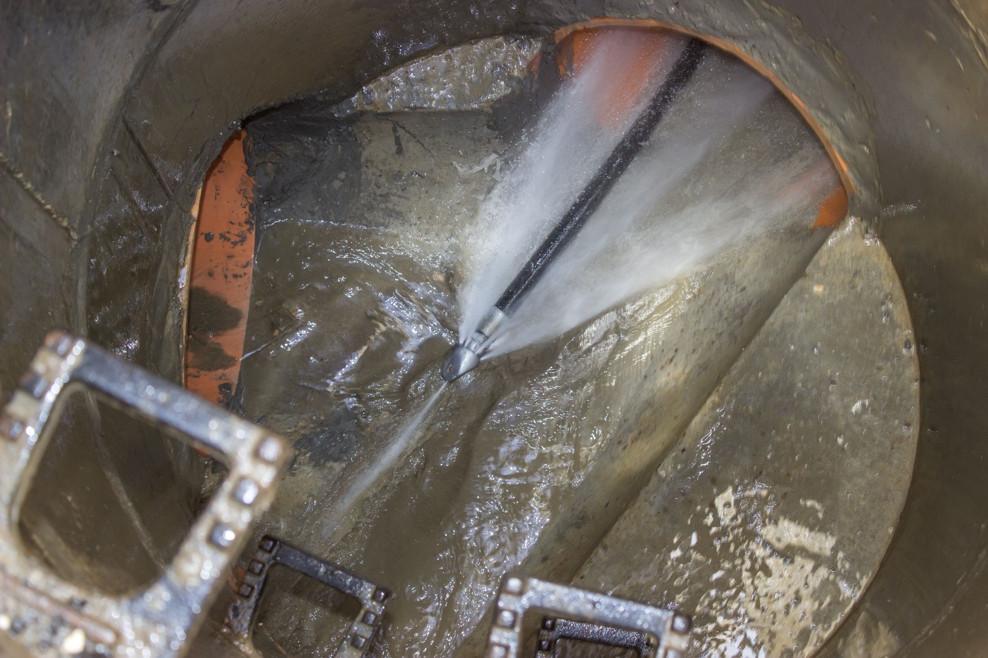 Interior view of a metal tank with water spraying across a wet, reflective surface
