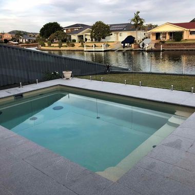 A swimming pool with a view of a river and houses in the background — Azure Pools Mid North Coast In Taree, NSW