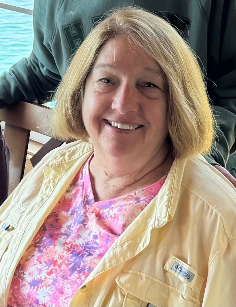 Group of smiling seniors at an event. Woman in black shirt waves.