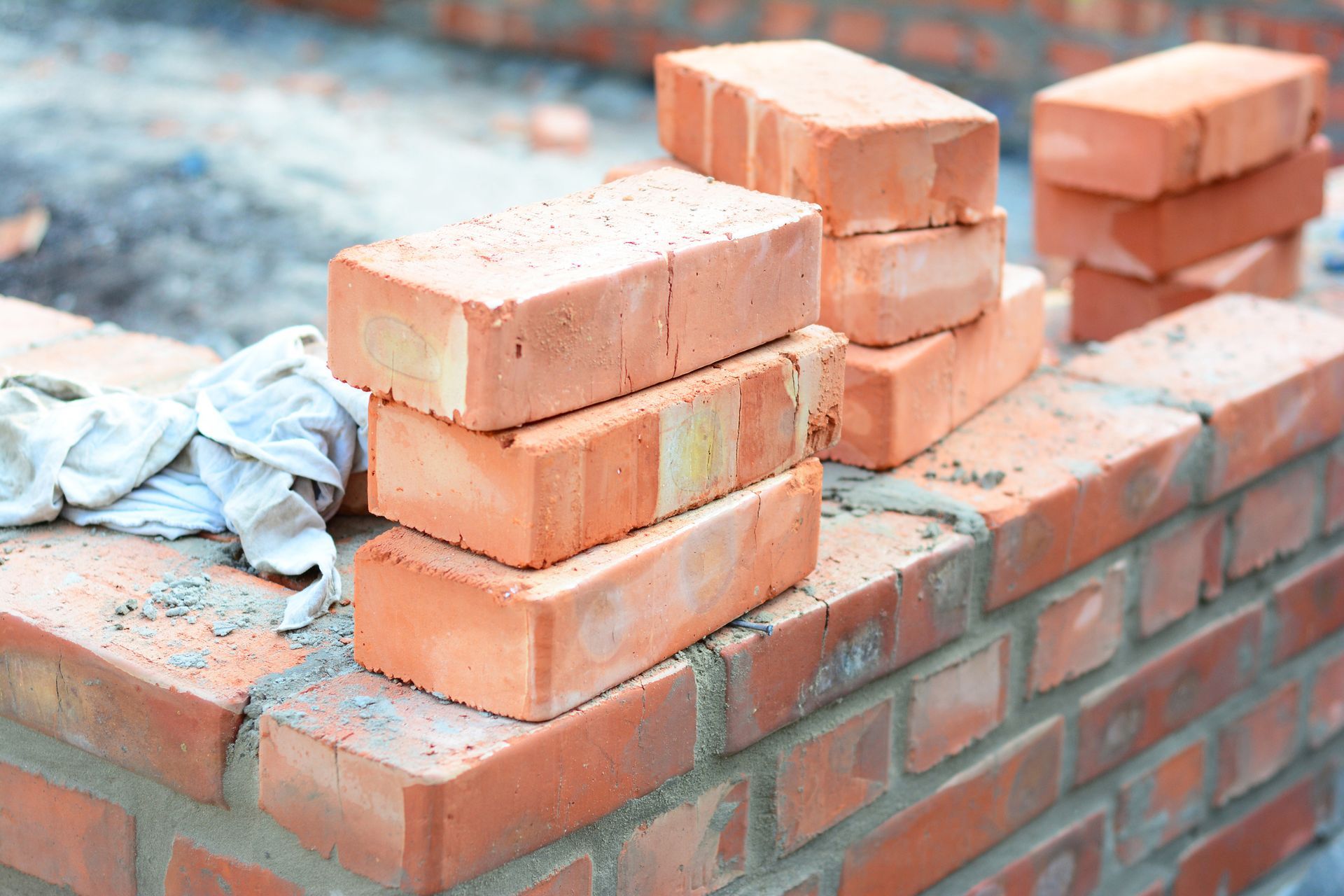 Bricks stacked on a partially constructed brick wall, construction site.