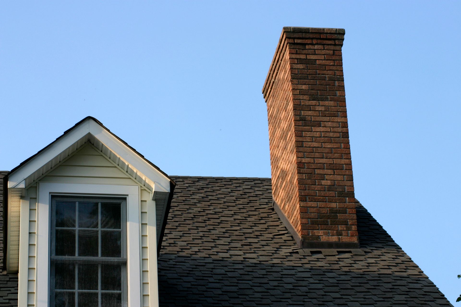 Red brick chimneys on a red tile roof with a skylight; blue sky in the background.