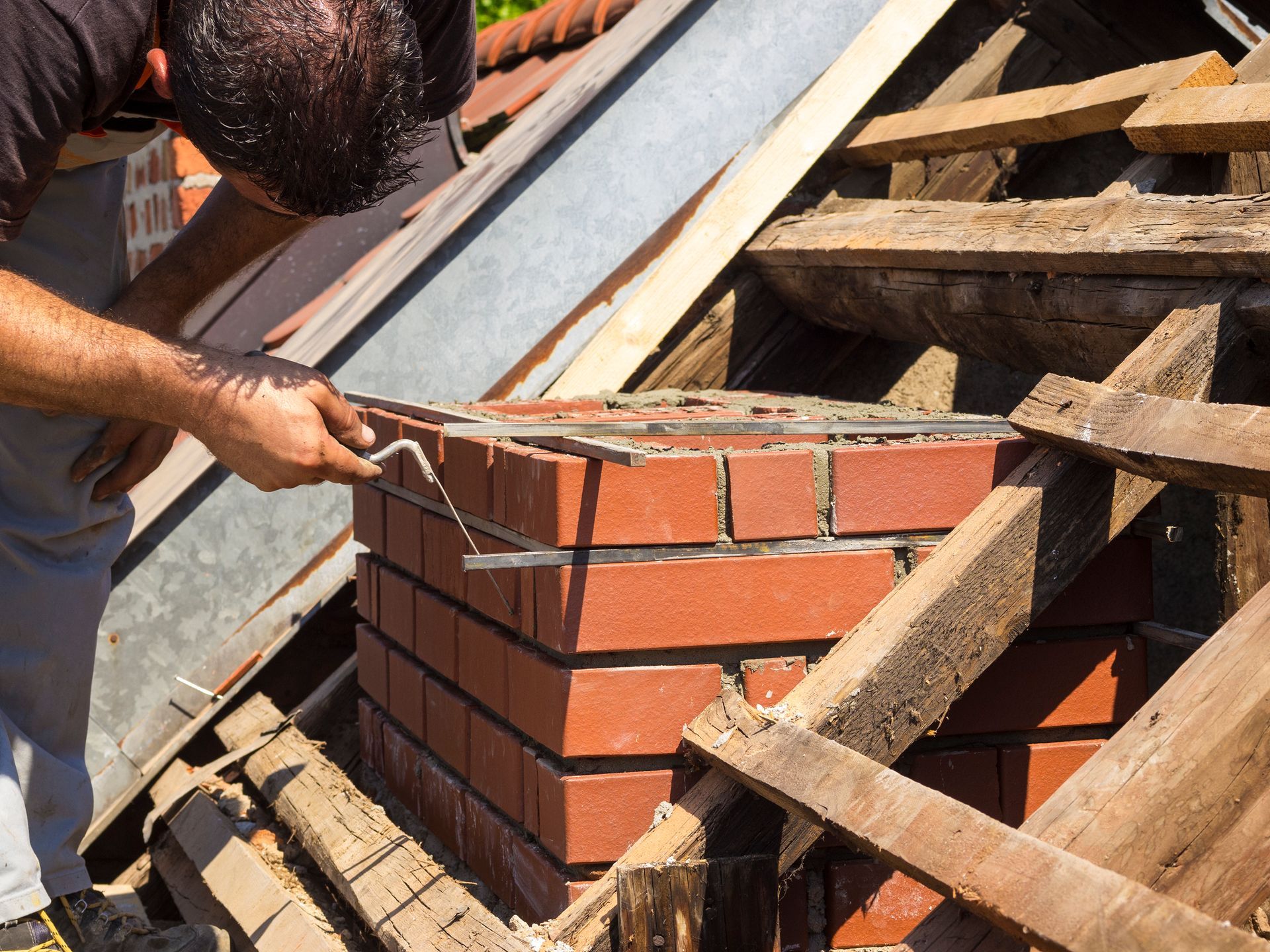 Man working on brick chimney roof repair.