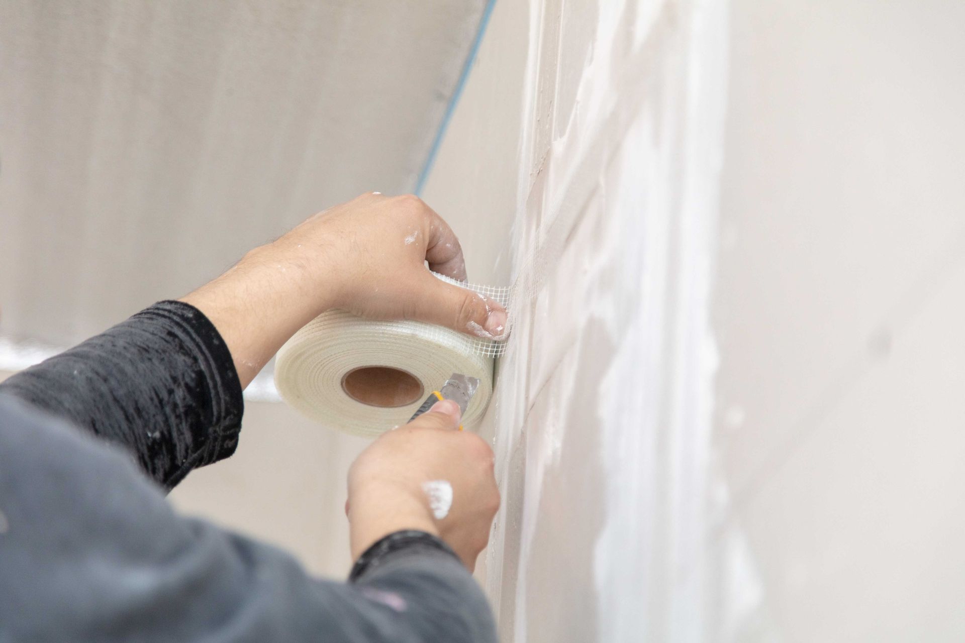 A person is cutting a piece of tape on a wall.