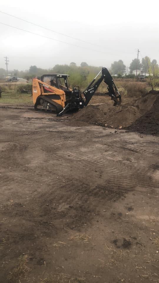 Orange and black construction vehicle digging in dirt pile on a cloudy day.