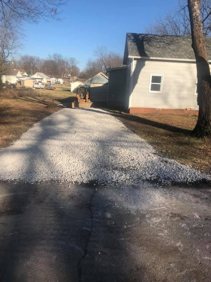Gravel driveway leading to a house on a sunny day.