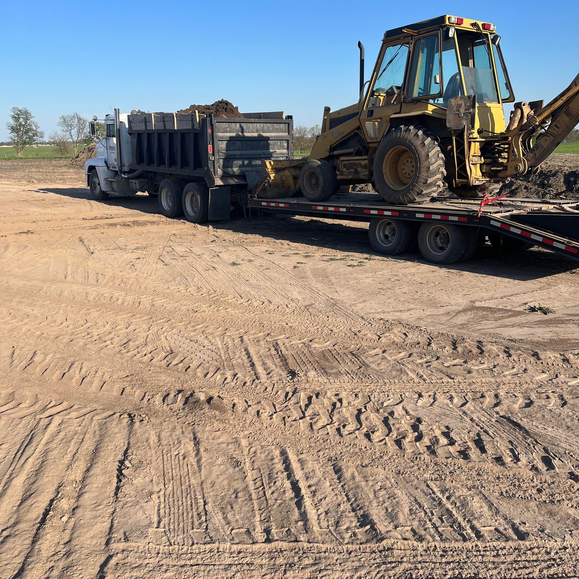 A yellow excavator is sitting on top of a pile of gravel.
