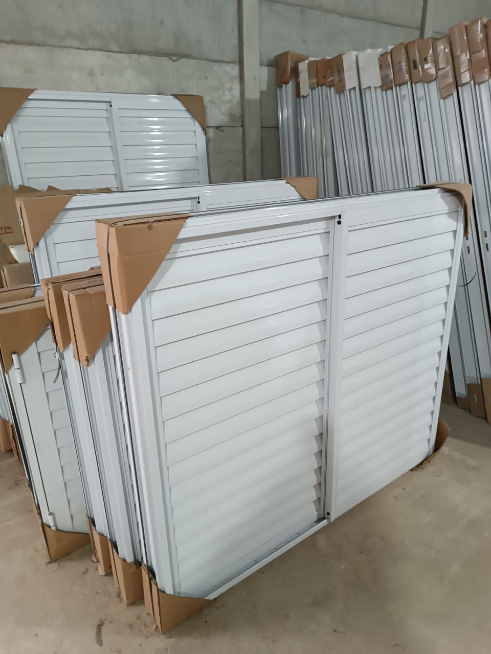 Un montón de persianas blancas están apiladas una encima de otra en un almacén.