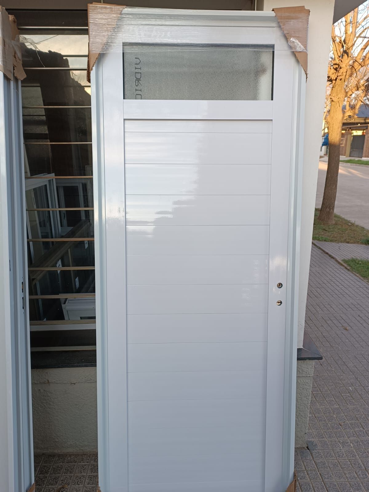 Una puerta blanca con una ventana está situada en el costado de un edificio.