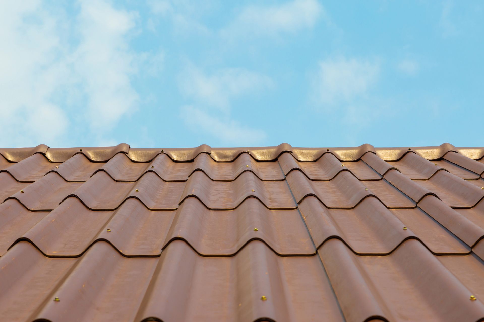 A close up of corrugated roofing with a blue sky in the background.