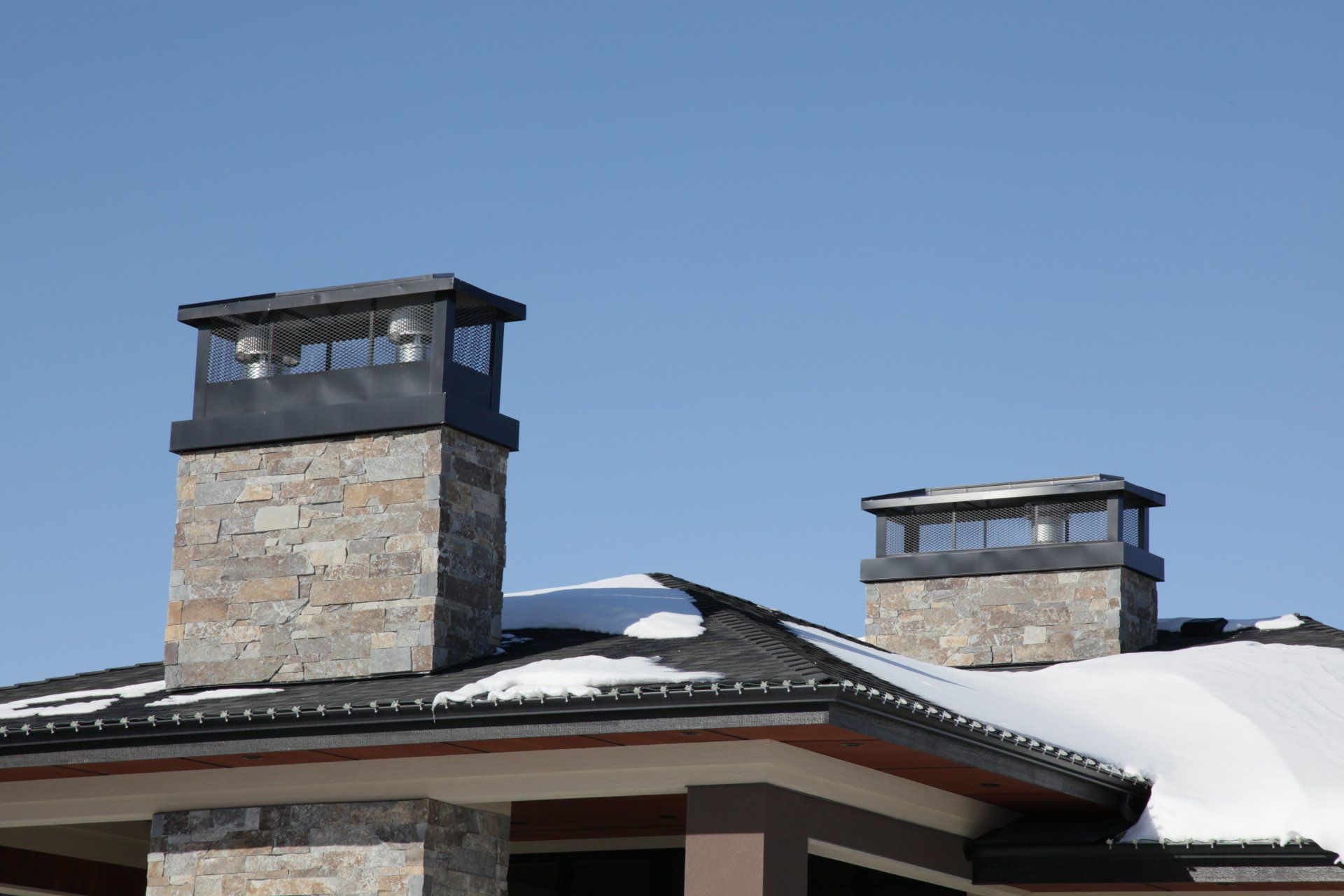 two chimneys on top of a house with snow on the roof
