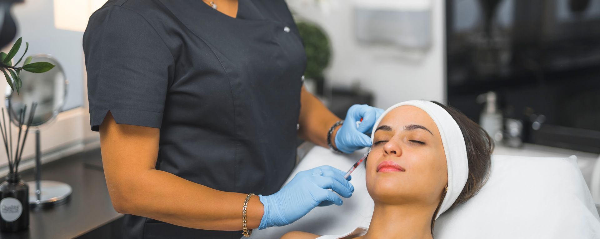 Aesthetician giving a woman a facial Botox injection at a clinic.