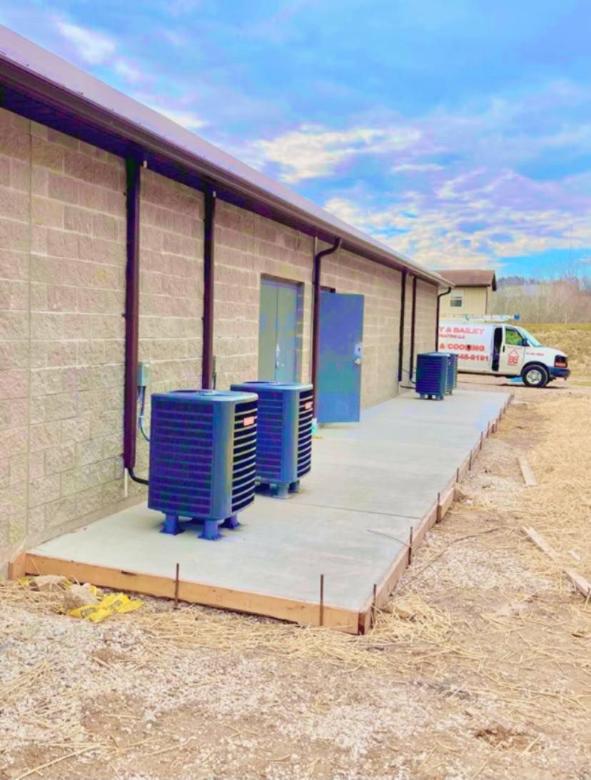Concrete walkway with AC units outside a building; a service van is in the background.