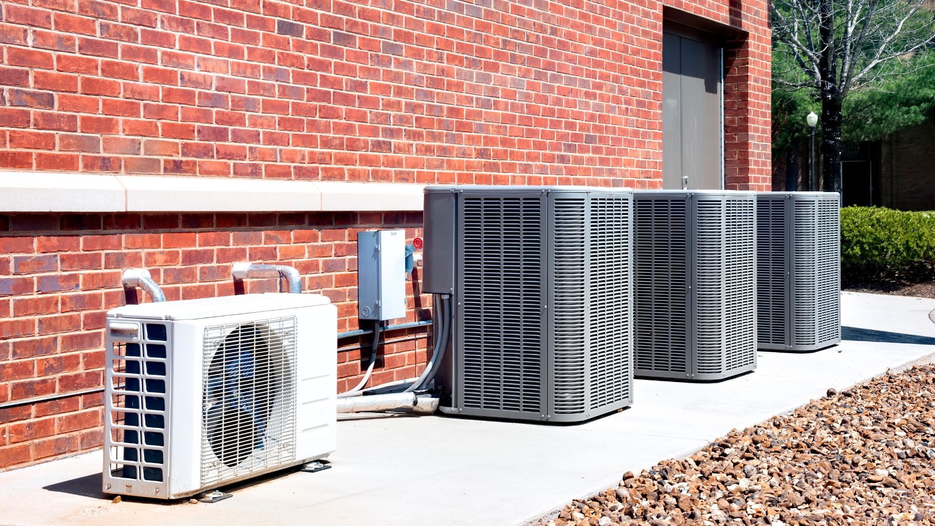 Air conditioning units next to a red brick building.