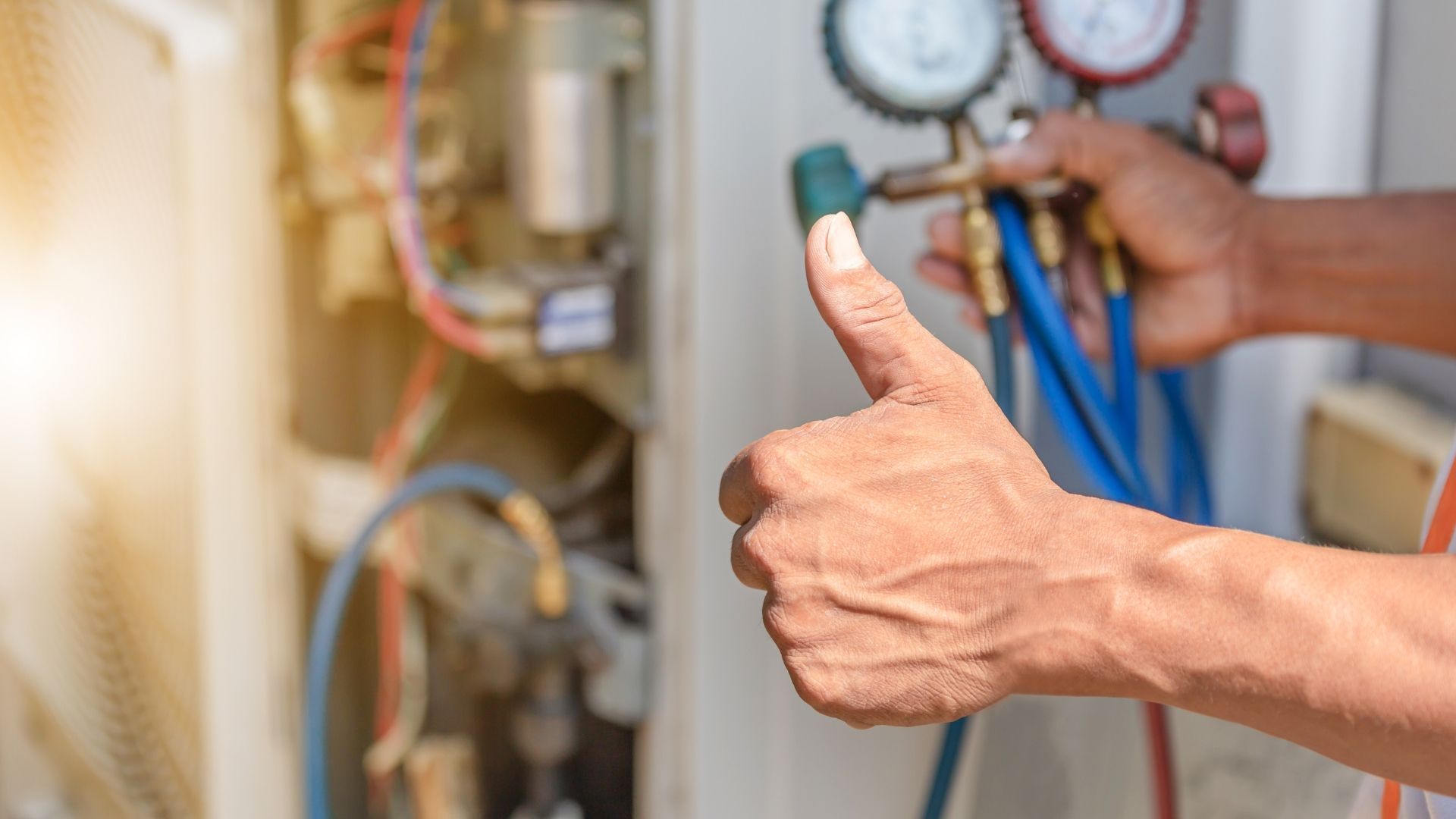HVAC technician gives thumbs up while servicing air conditioning unit.
