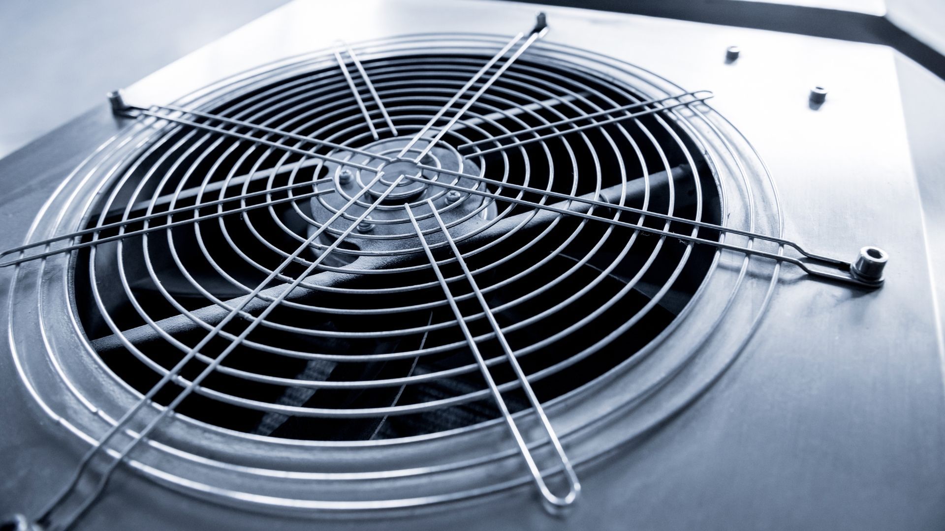 Metal fan with a protective grill, installed in a panel.