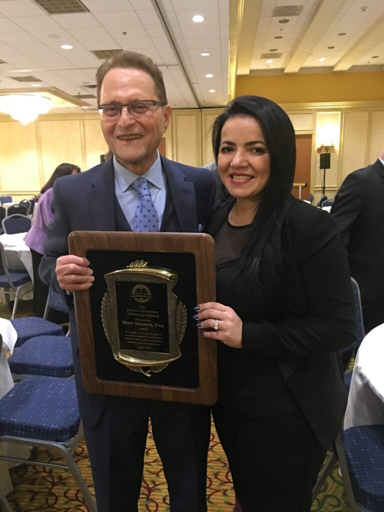 Man and woman holding plaque at an event, both smiling.