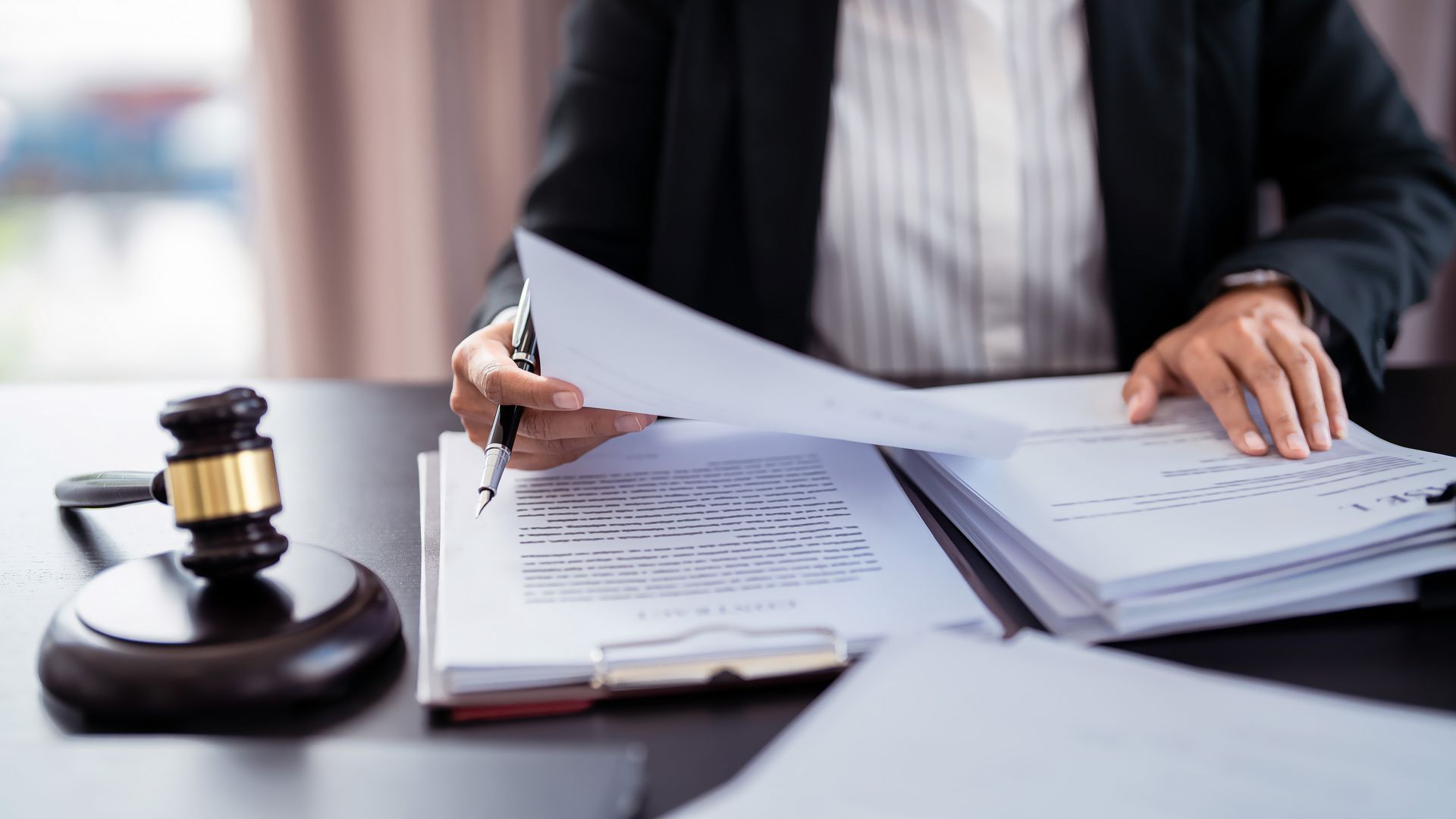 Person in a suit reviews documents at a desk, gavel in foreground.