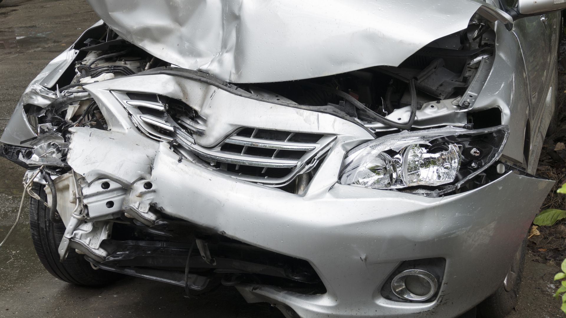Damaged silver car, front end crushed from a collision.