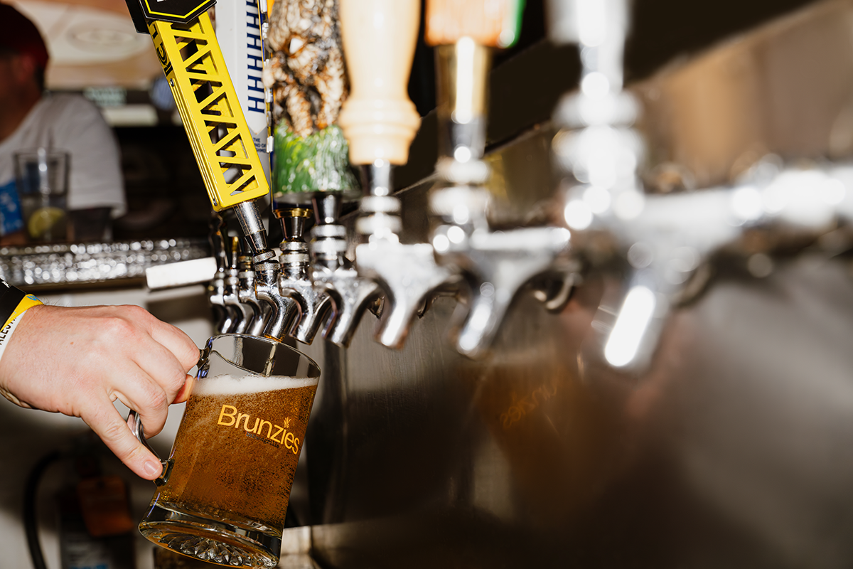 A person pours beer from a tap into a glass at a bar.