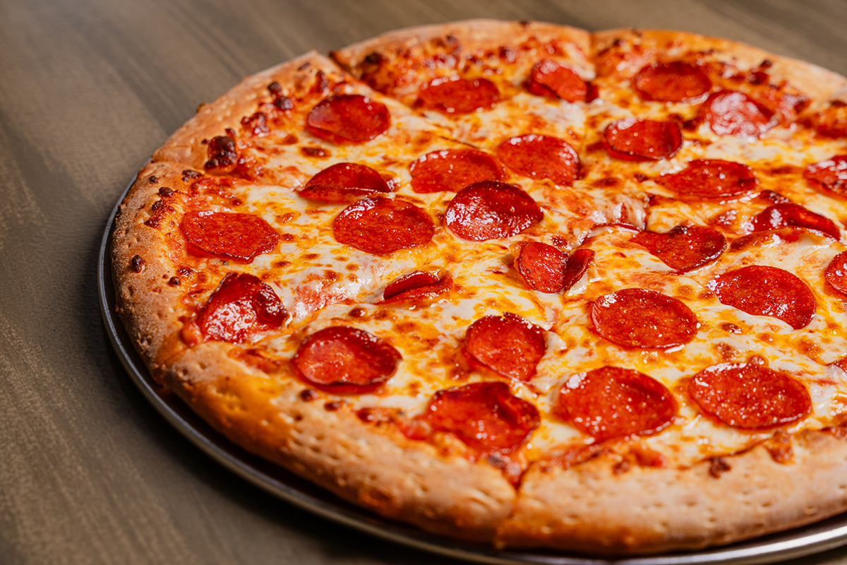 Pepperoni pizza on a metal tray, crust, melted cheese, and pepperoni.