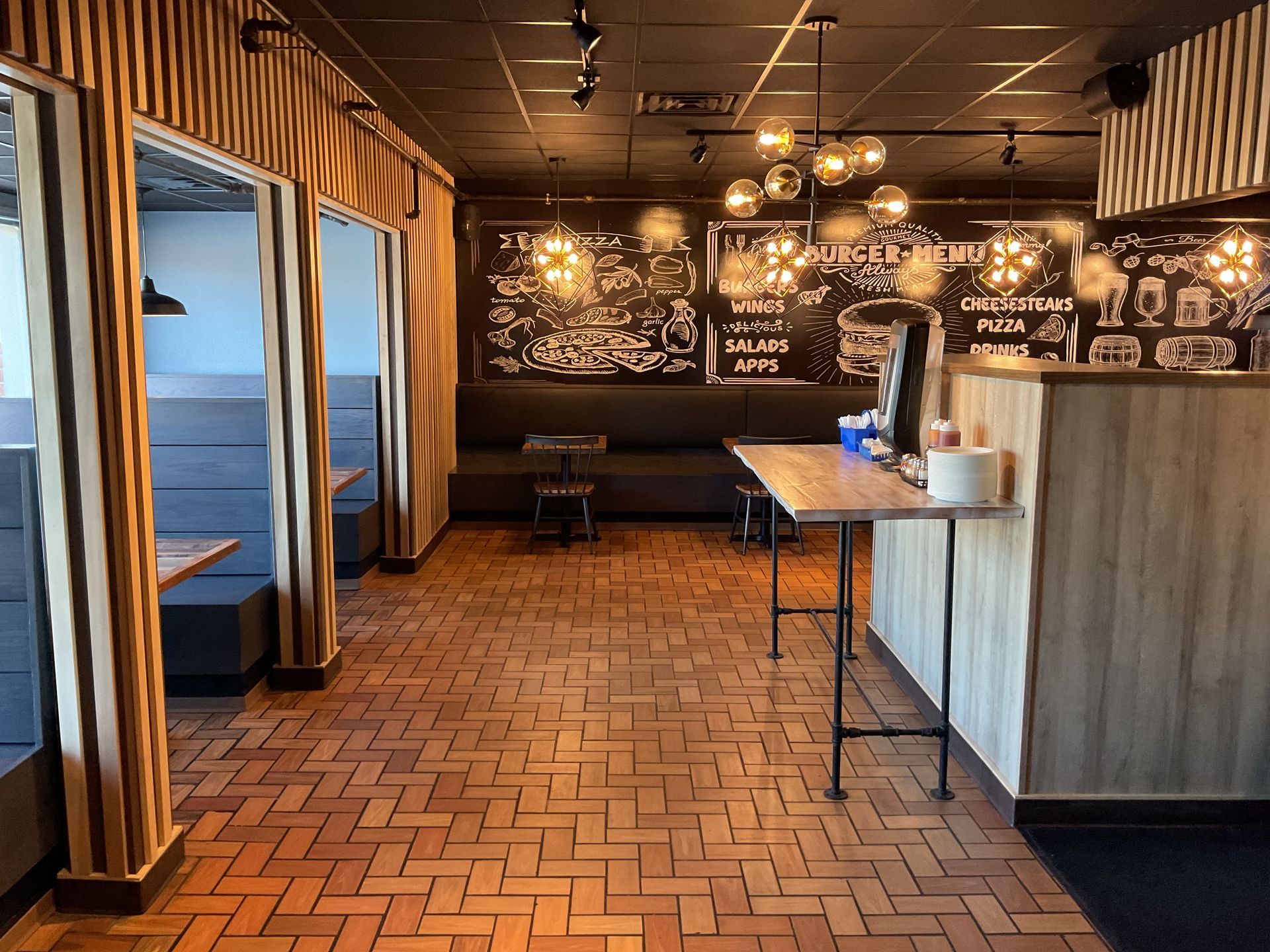 Restaurant interior with wood paneling, booths, and a counter. Chalkboard menu on the back wall.
