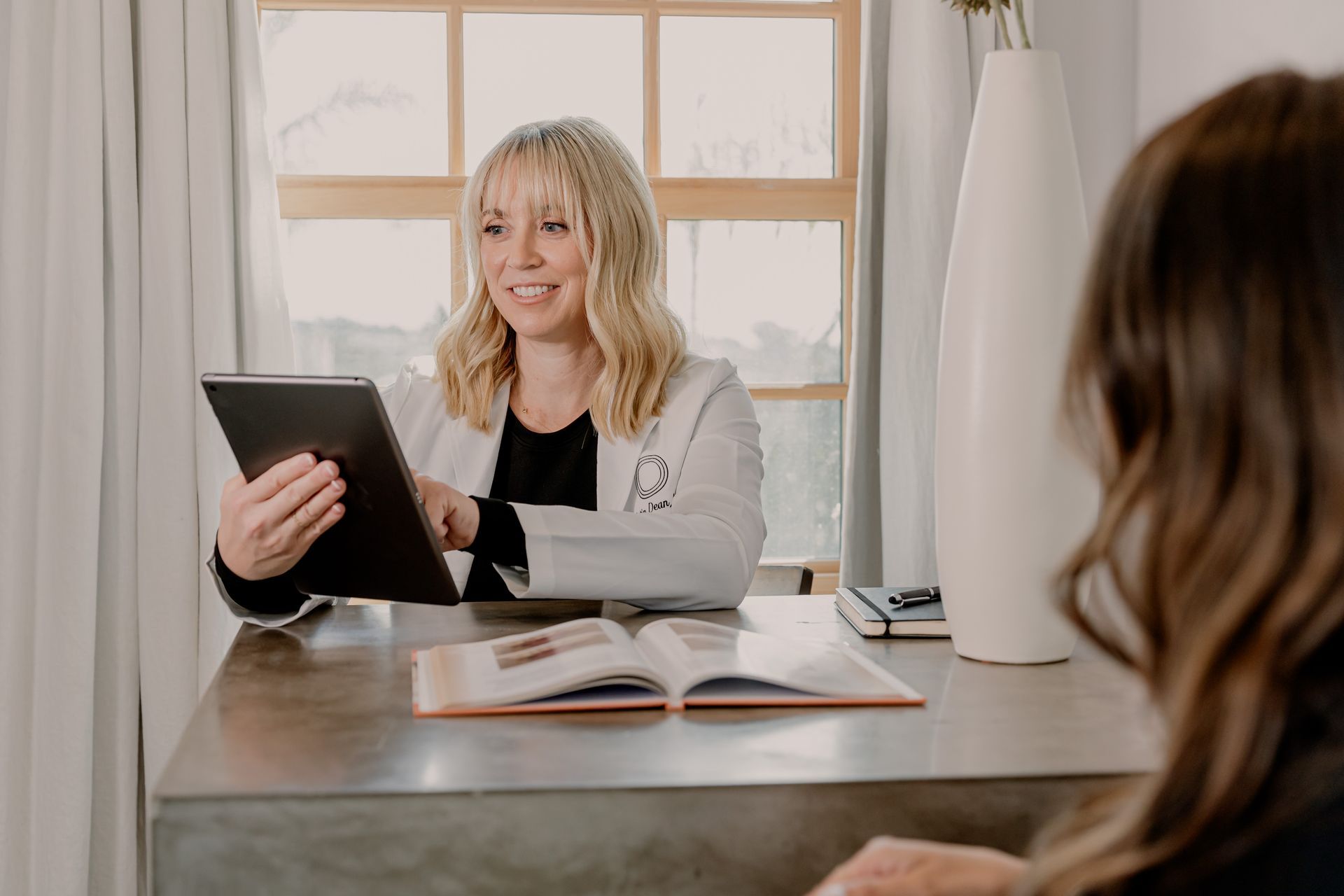 A woman is sitting in a chair while a doctor holds a syringe for a medical weight loss treatment.