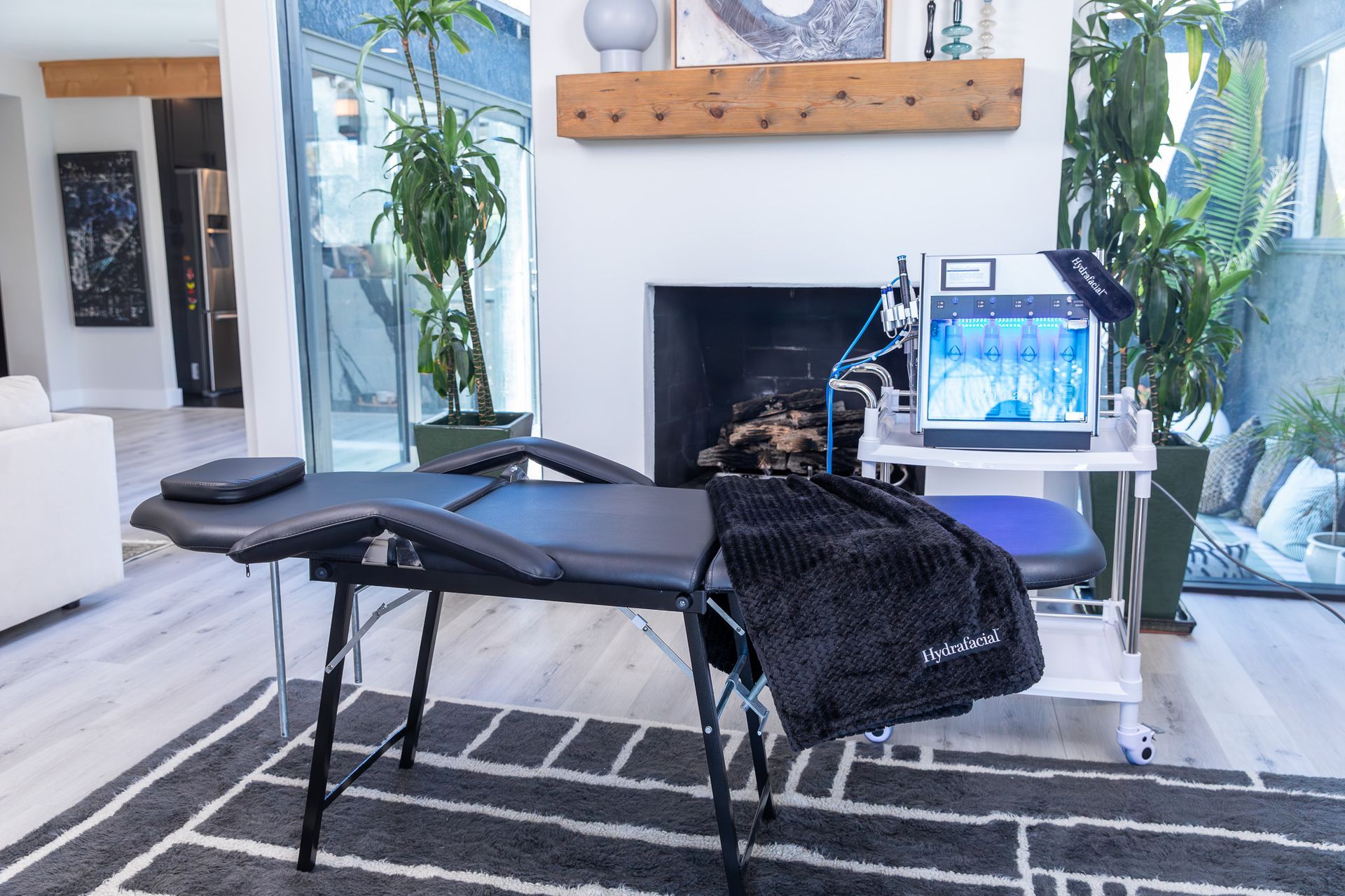 Black massage table and device in a room with a fireplace and plants.