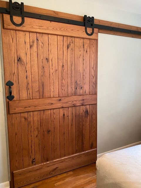 A Wooden Sliding Barn Door Is in A Bedroom Next to A Bed | Narvon, PA | JDH Custom Millwork