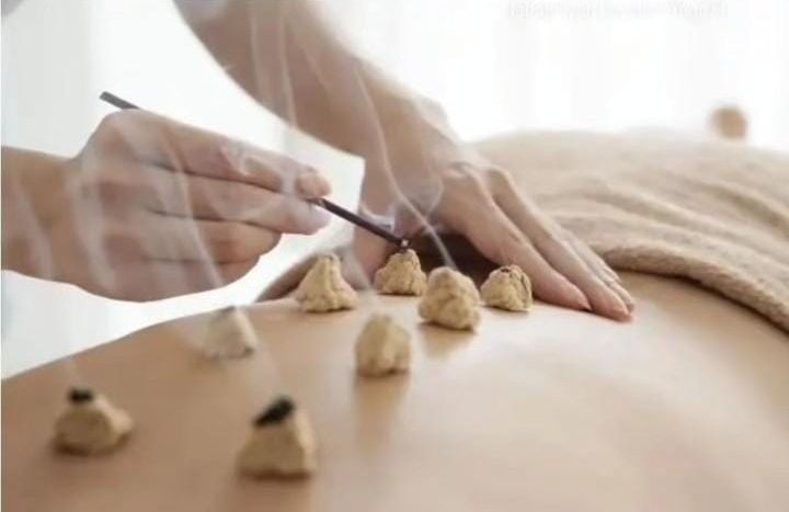 Manos colocando piedras calientes sobre la espalda desnuda de una persona durante un masaje de spa.