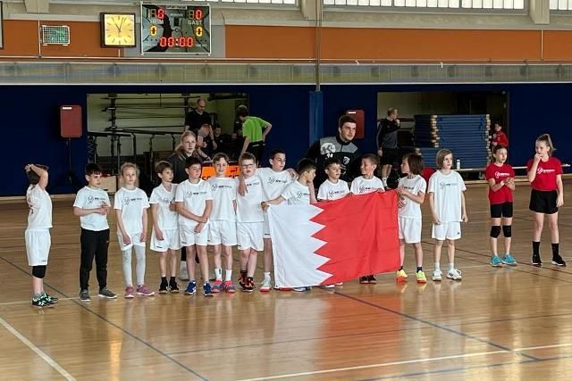 Eine Gruppe Kinder steht auf einem Basketballplatz und hält eine Fahne.