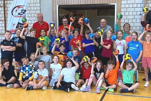 Eine Gruppe Kinder sitzt auf dem Boden und hält Bälle in den Händen.