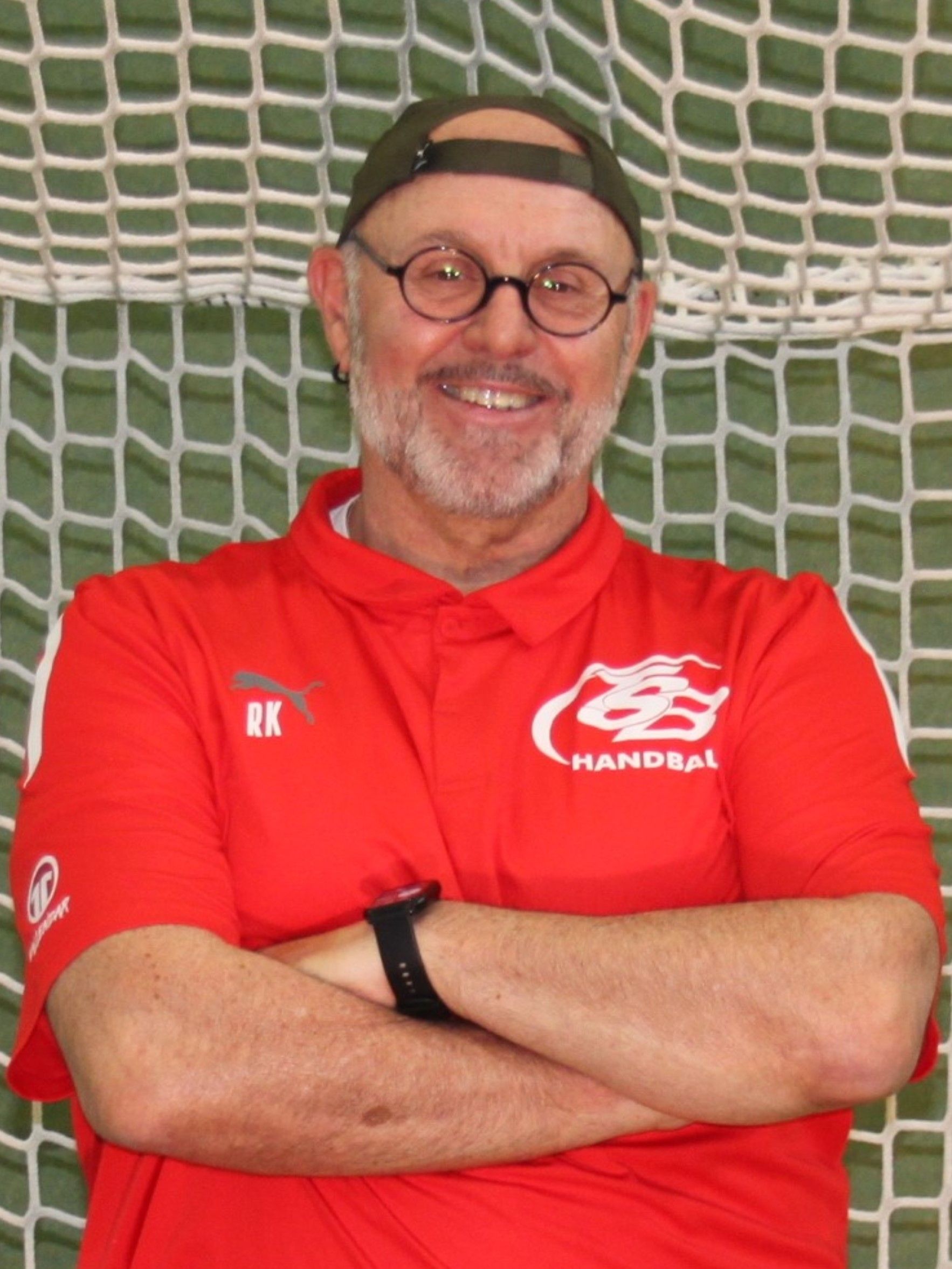 Ein Mann trägt ein rotes Poloshirt mit dem Buchstaben M darauf