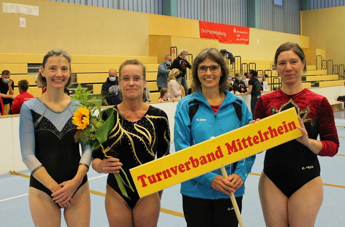 Vier Frauen halten ein Schild mit der Aufschrift Turnverband Mittelrhein