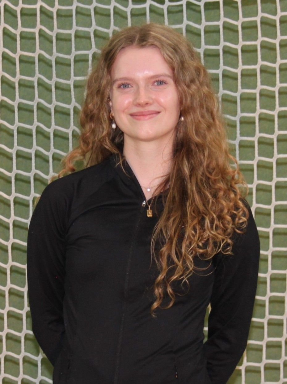 Eine junge Frau mit lockigem Haar steht vor einem Netz.