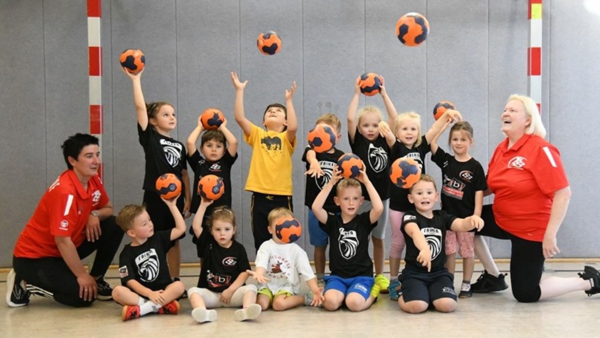 Eine Gruppe Kinder posiert für ein Foto und hält dabei Basketbälle in den Händen.
