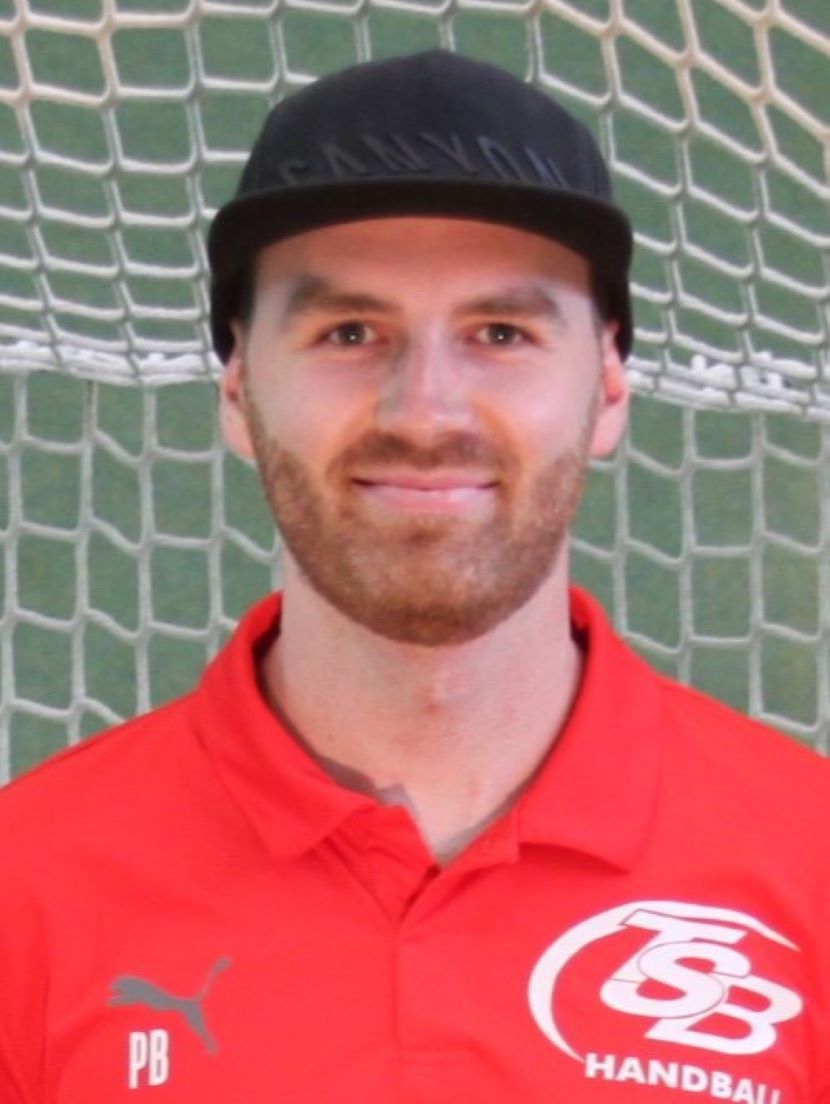 Ein Mann, der ein rotes Hemd mit der Aufschrift „PB“ trägt