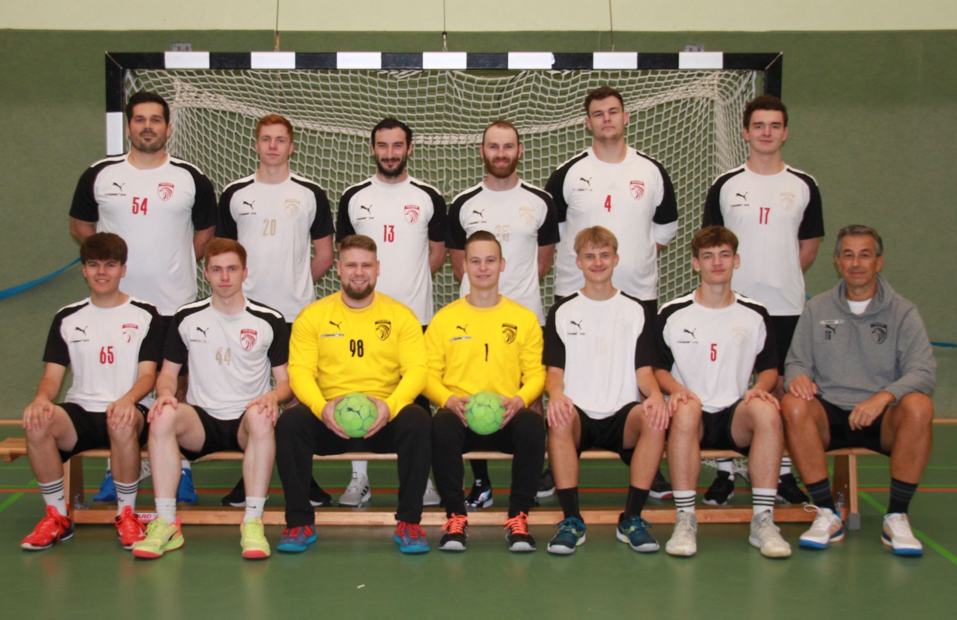 Eine Gruppe von Leuten spielt in einer Turnhalle Fußball.