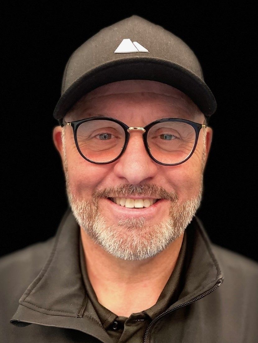 Ein Mann mit Brille und Hut lächelt in die Kamera.