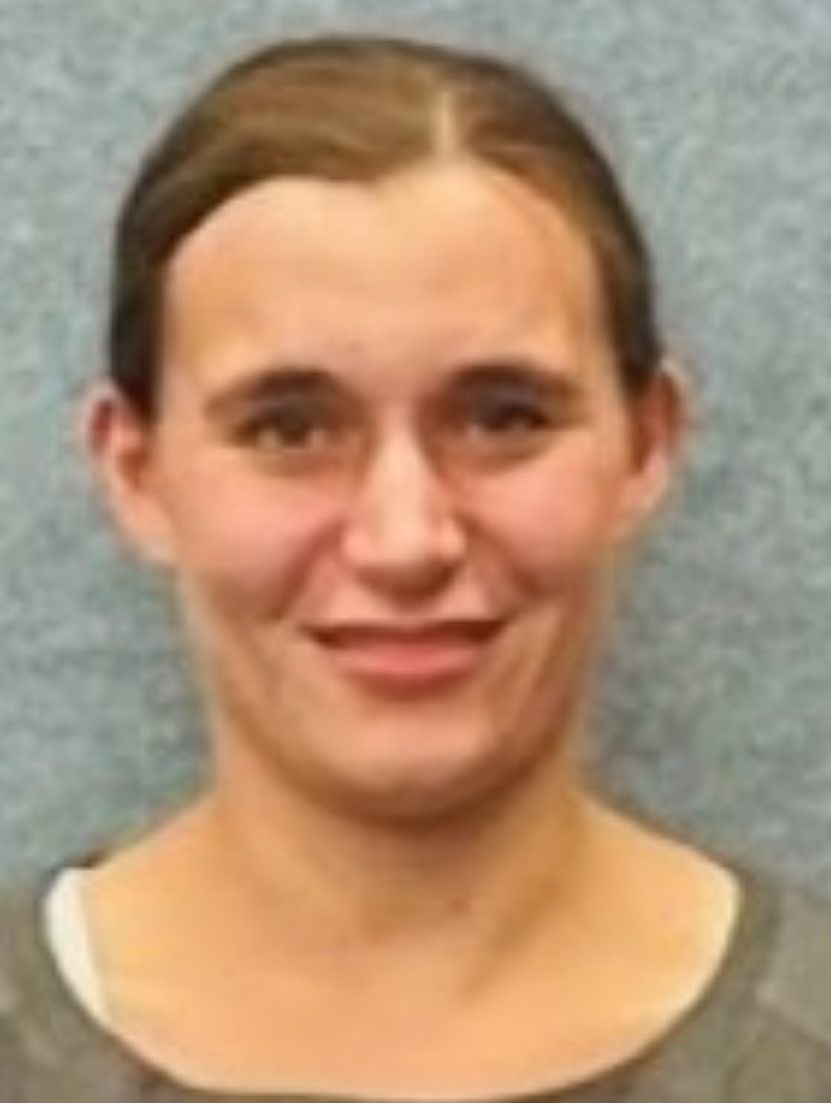 Eine Frau in einem grauen Hemd lächelt in die Kamera